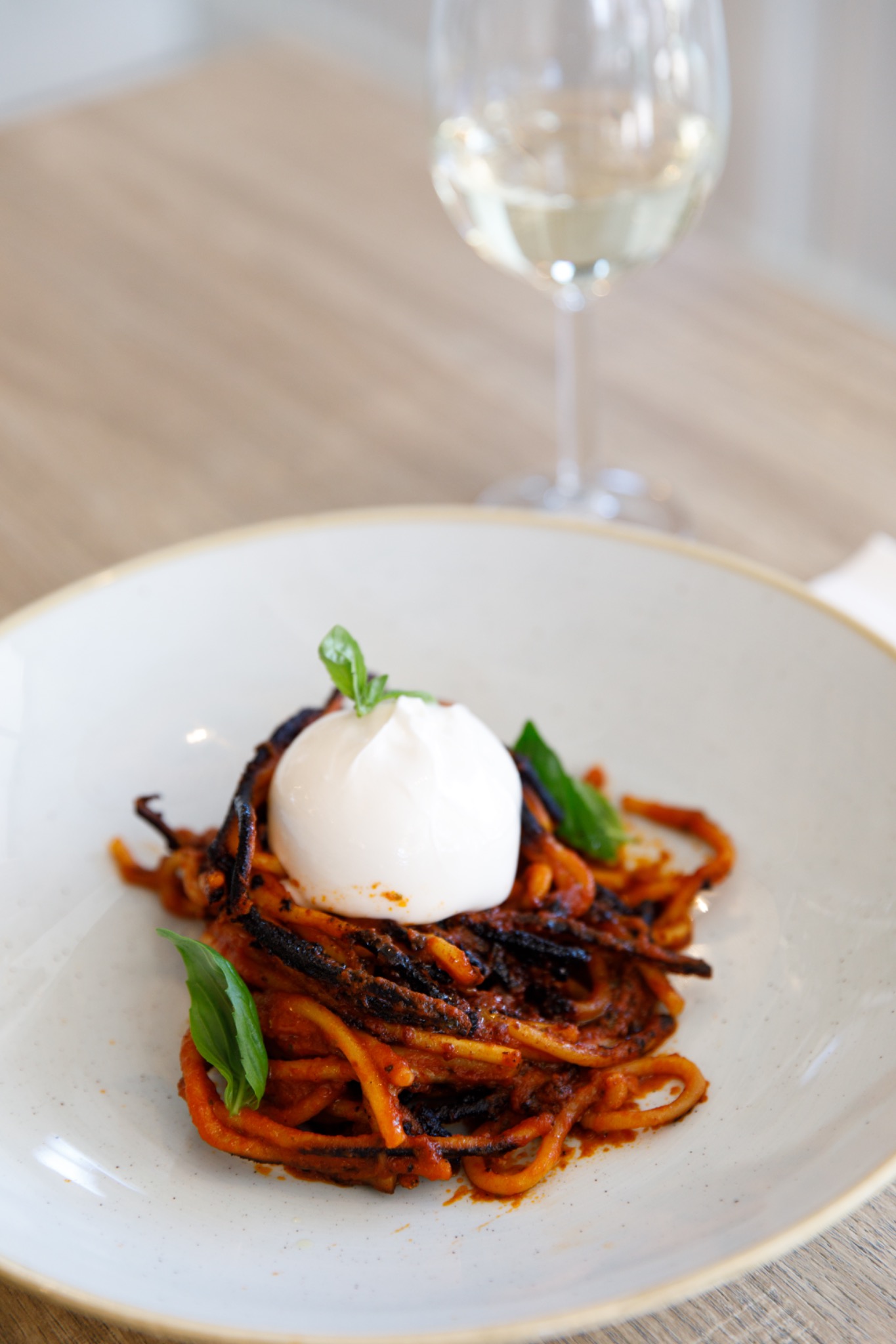 Spaghetto all’assassina con burrata, servito su piatto bianco