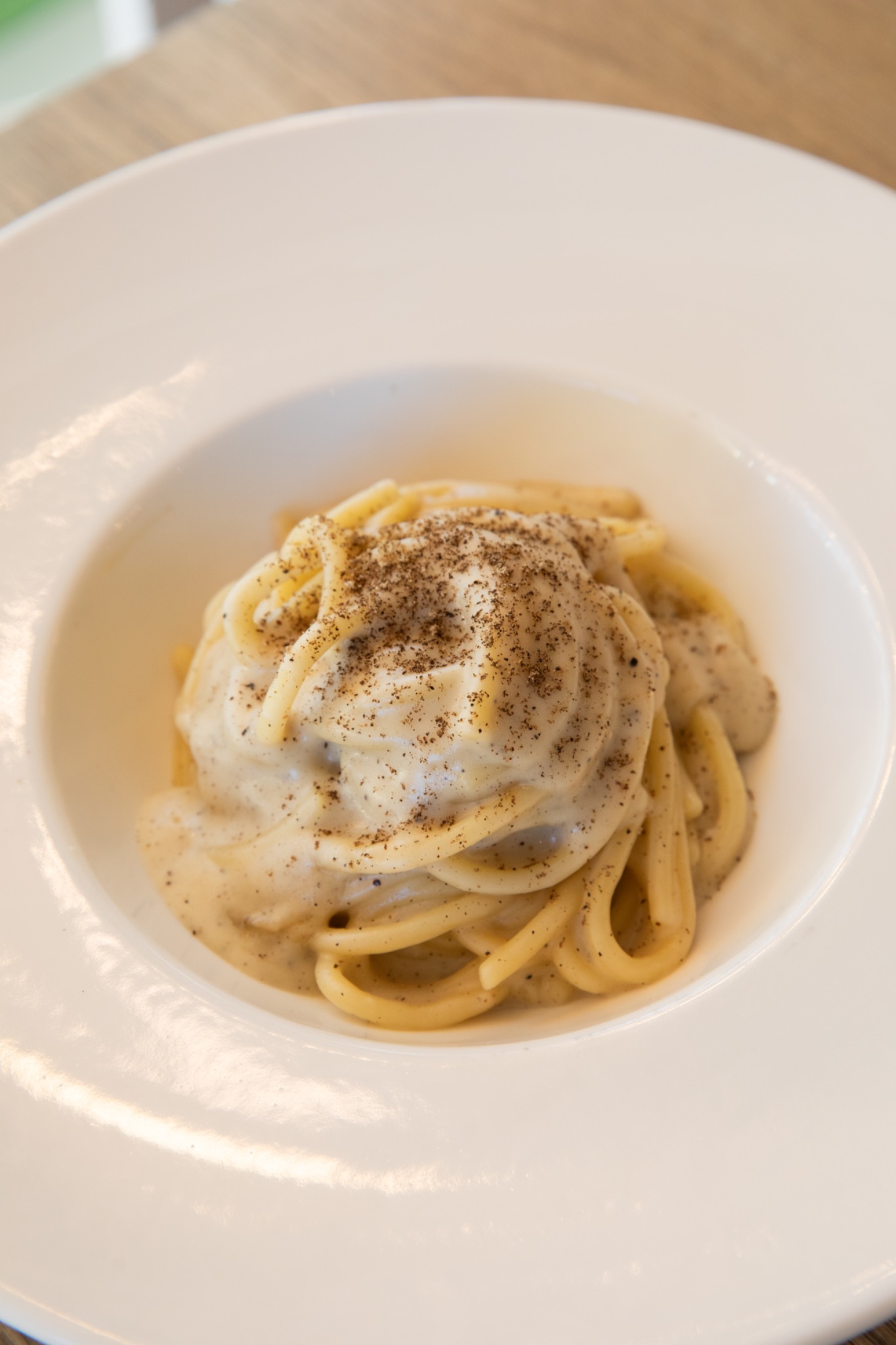 Spaghettone cacio e pepe in un piatto bianco